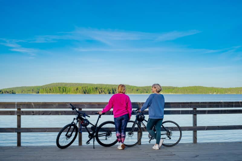 Kaksi naista pyörien kanssa järven rannalla